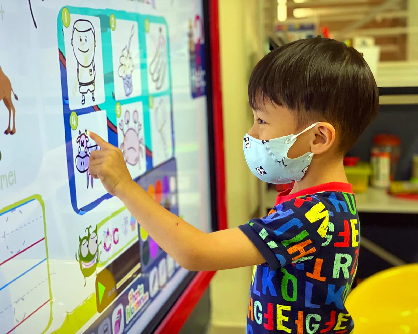 A child pointing at a Phonics Monsters page on a classroom interactive whiteboard